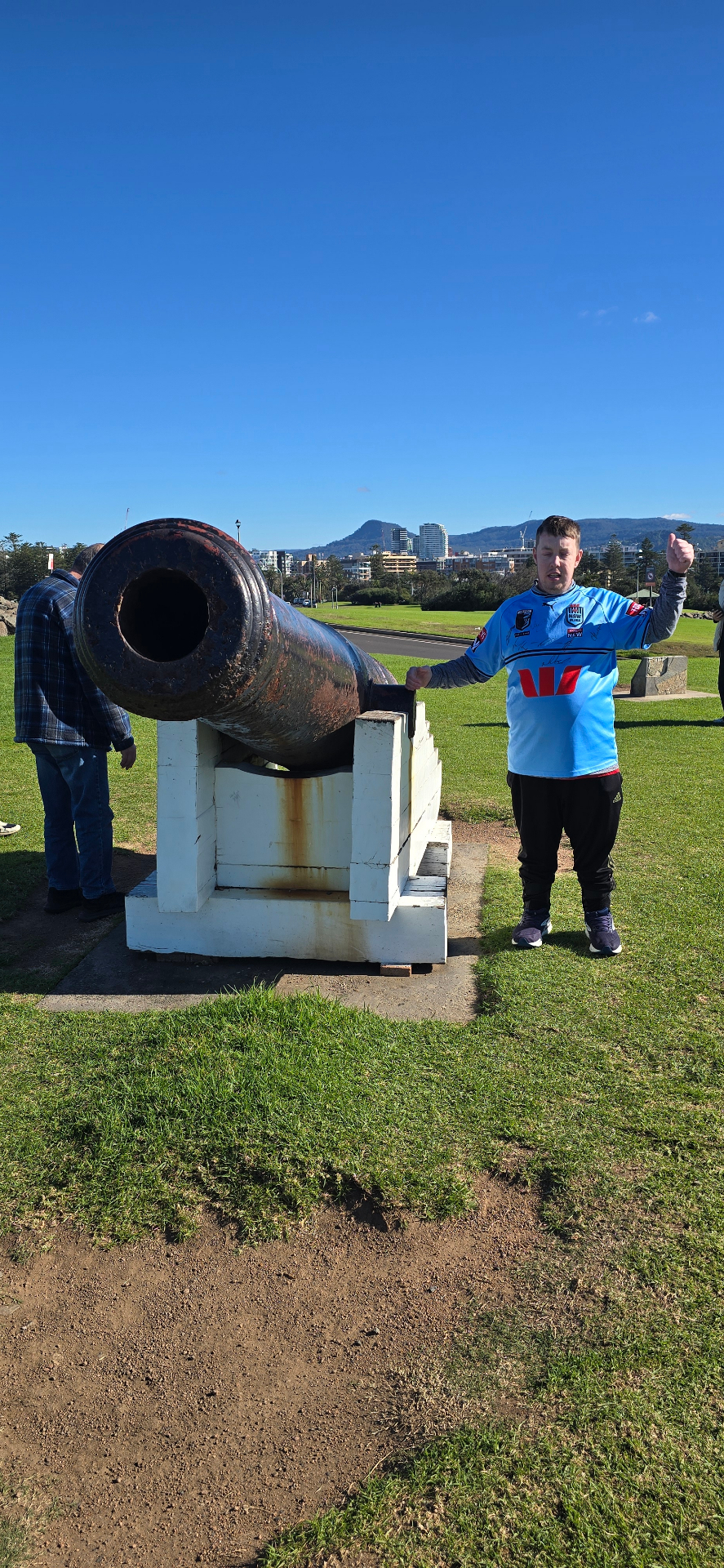 A participant giving a thumbs up beside a historic cannon at Wollongong