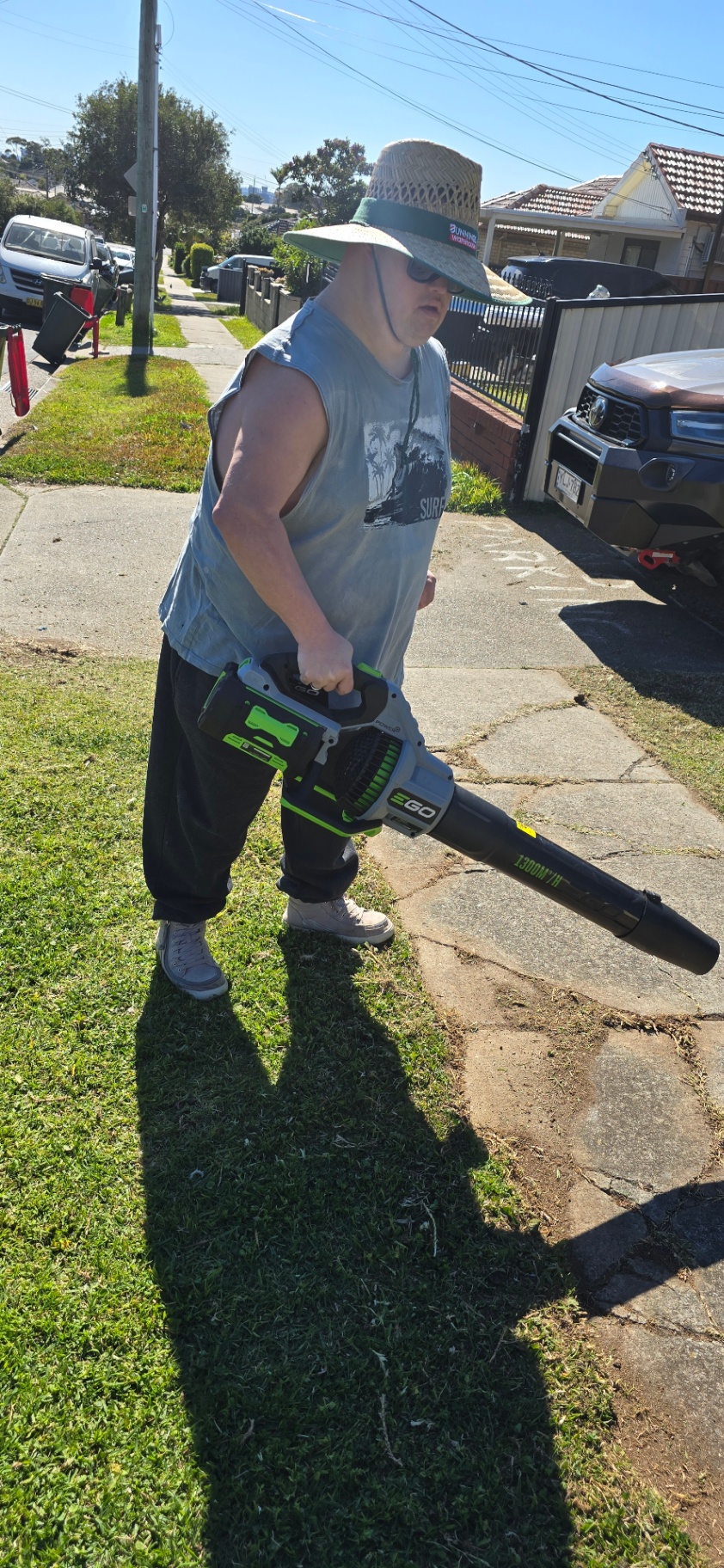 A participant using a leaf blower to tidy a front lawn