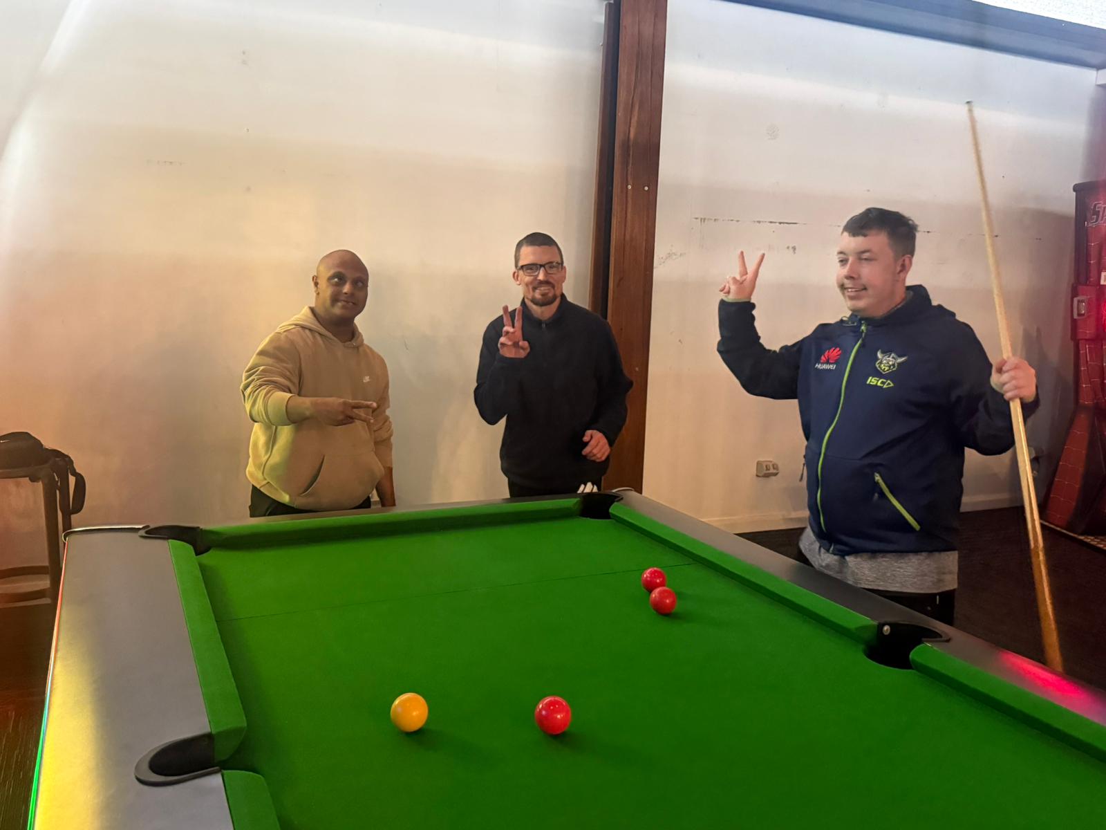 Three mates enjoying a game of pool together