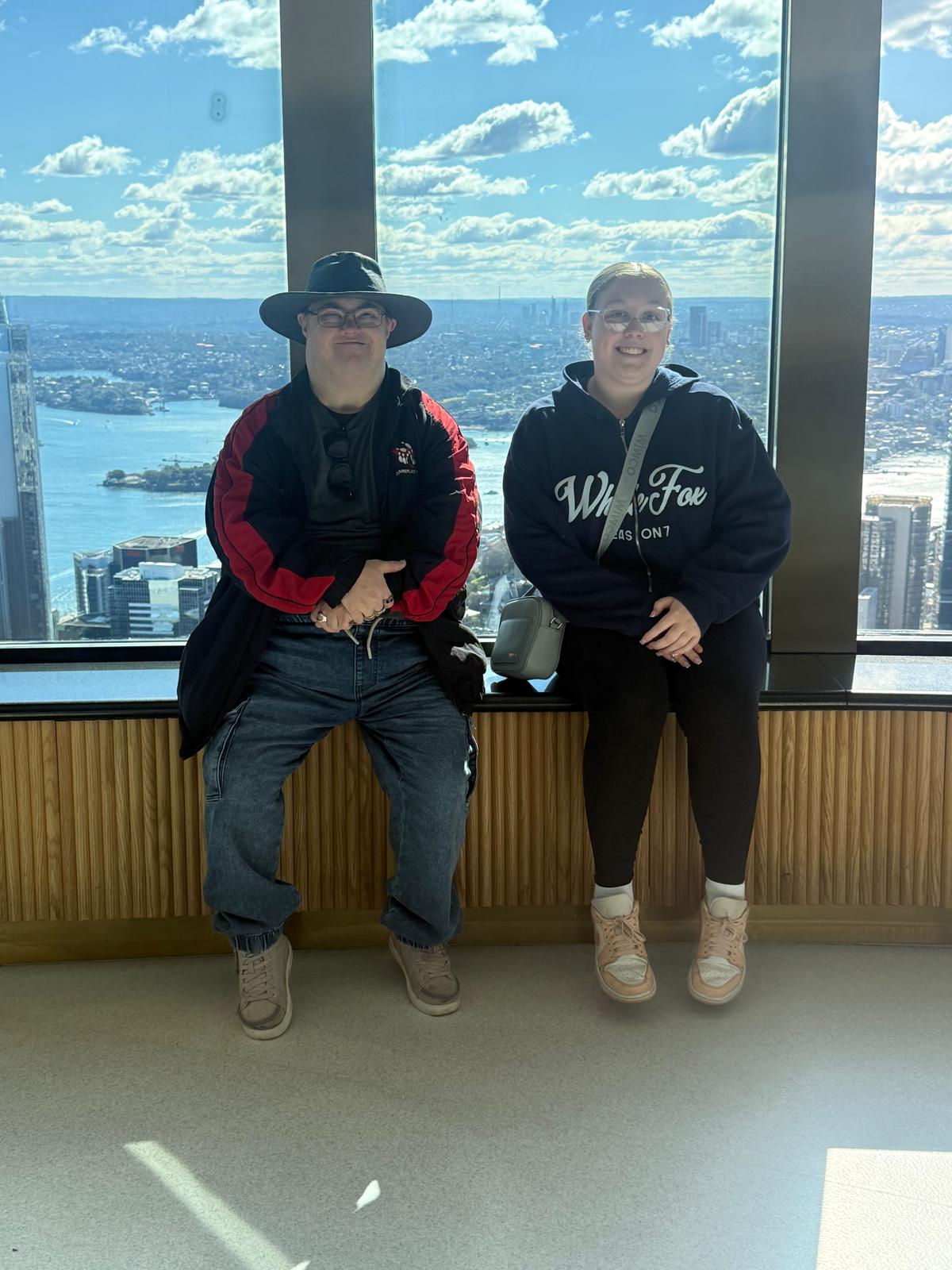 Two participants at the Sydney Tower Eye with the harbour behind them