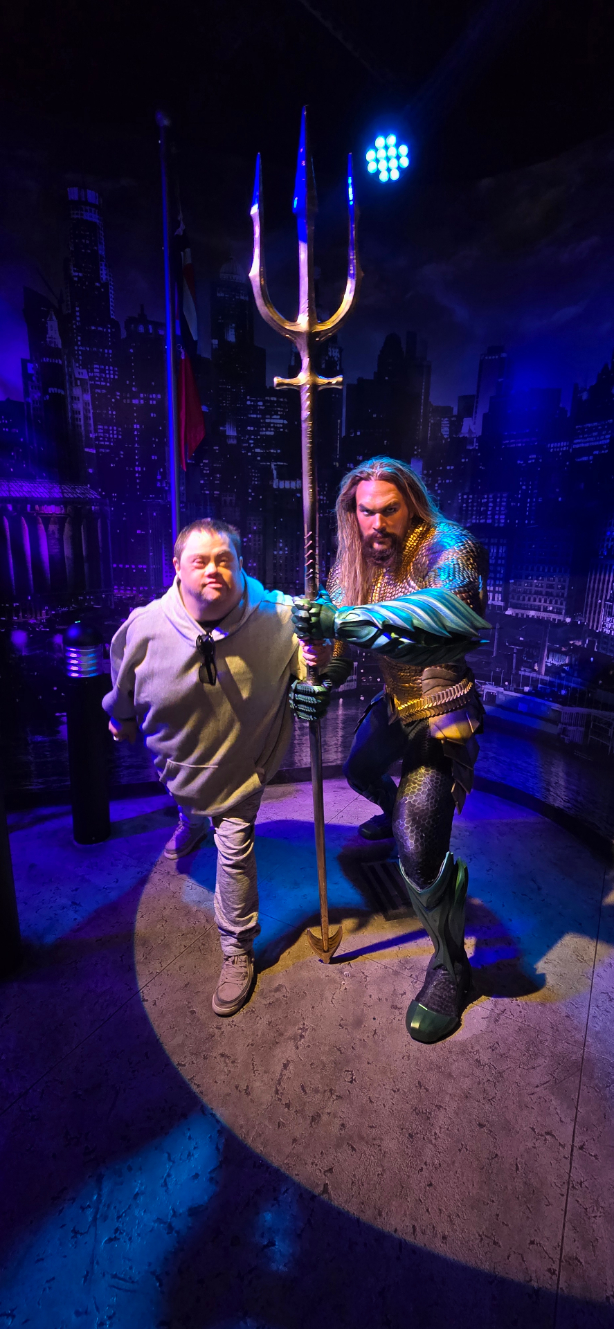 A participant posing with an Aquaman figure at a wax museum
